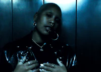 a woman in a black leather jacket standing in an elevator