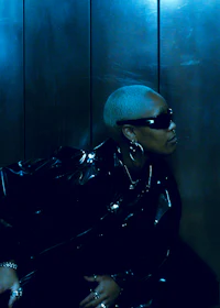 a woman in a leather jacket leaning against a wall